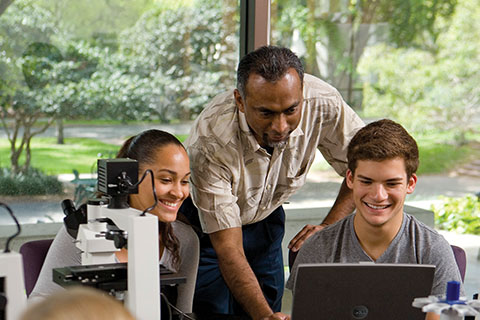 A professor helps students in a biology lab